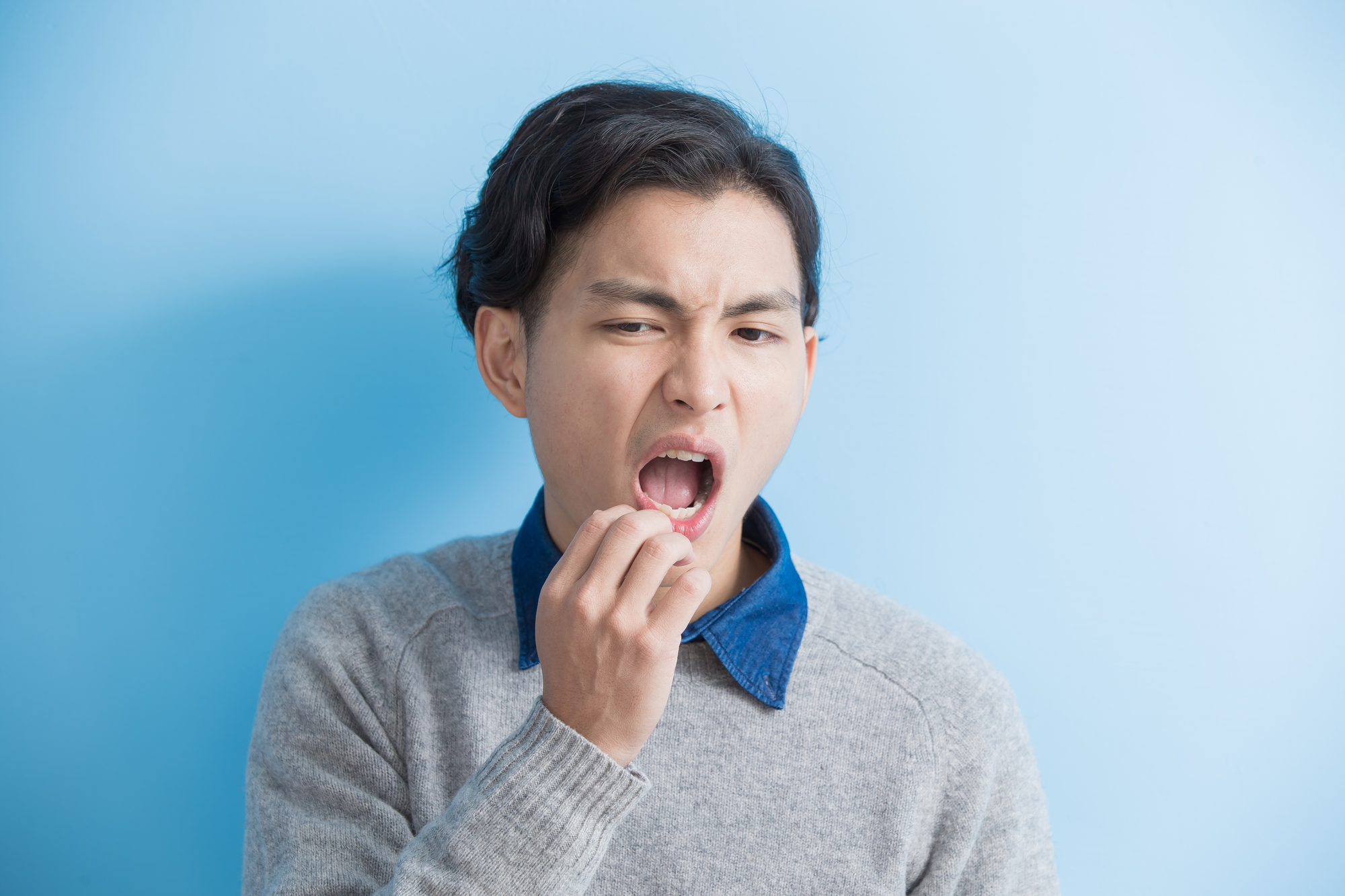 Asian man with infected tooth on blue background