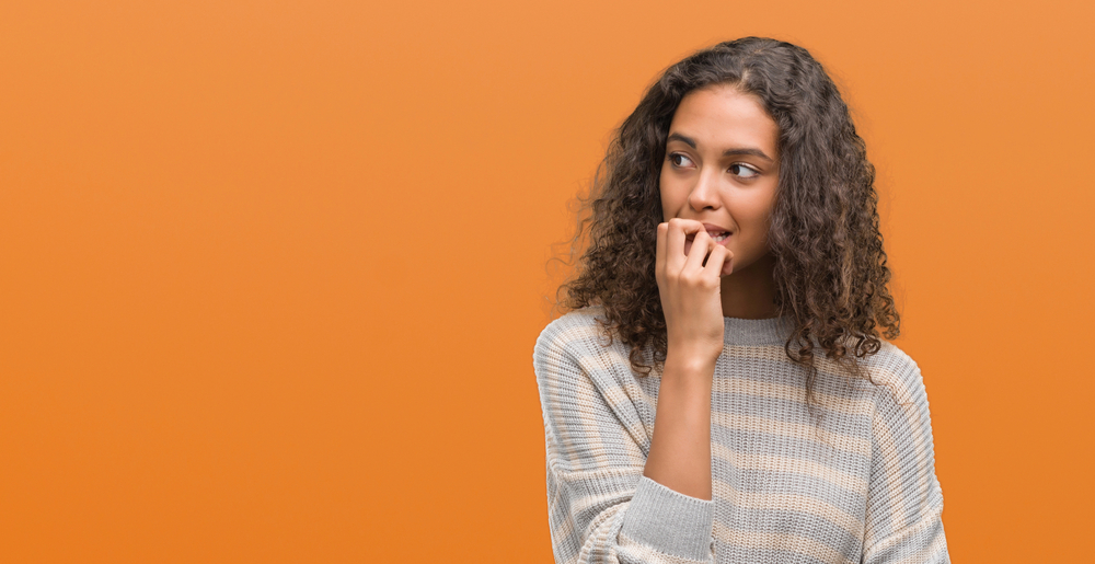 woman embarrassed by crooked teeth on orange background