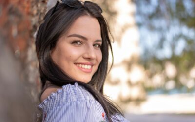 young woman with brown hair smiling and looking over her shoulder