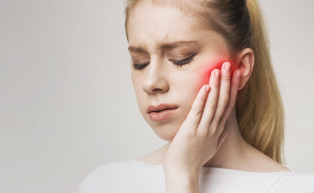 woman with a toothache, red spot on the side of her face, woman putting hand on her face because of toothache