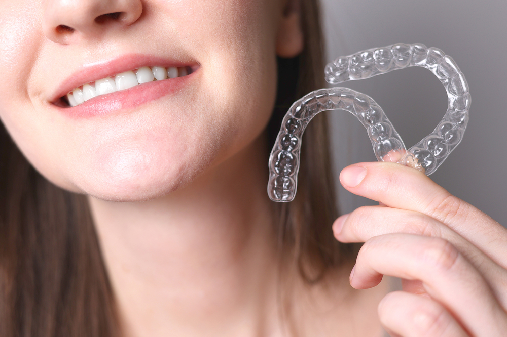 woman holding two clear aligners